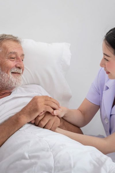happy-nurse-holding-elderly-man-hands-with-blanket-bedroom-nursing-home-v